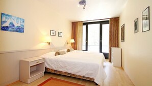 Une chambre à coucher avec un lit, des tables de chevet, une commode, une fenêtre avec des rideaux et un tableau au mur.