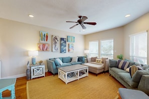 Relax in style with a sofa, loveseat, and coffee table, surrounded by artwork and a ceiling fan for comfortable ventilation.