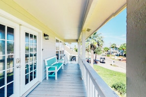 Step outside to a charming covered porch with a bench and double doors leading to the interior.