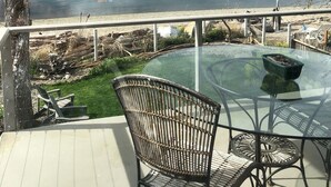 A glass table with two chairs on a deck overlooking a lake. - Prime Sandy Beachfront Home with Mountain Views - 5 minutes to Gig Harbor/Tacoma (Gig Harbor)