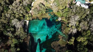 An aerial view of a property with a large rectangular water body surrounded by dense forest. - Rainbow River Serene Garden House (Dunnellon)