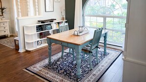 Un coin repas avec une table et des chaises en bois, entouré d’étagères et d’une grande fenêtre donnant sur un paysage verdoyant.