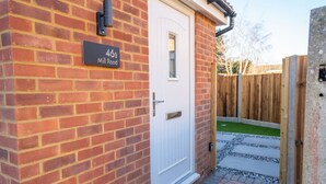 A brick house with a white door and a mailbox on the wall. - Skyway First Floor Apartment is a 2 bedroom apartment with parking in Three Bridges (West Sussex)