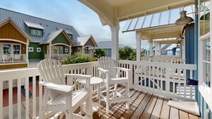 Ein überdachter Außenbereich mit weißen Adirondack-Stühlen und einer Holzterrasse.