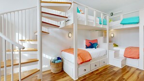 A multi-level bunk bed room with a white staircase and wooden flooring. - Palmilla Beach designer retreat with golf, pool & chef's kitchen - walk to beach (Port Aransas)