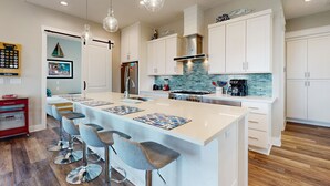 Una cucina moderna con un'isola grande, sgabelli da bar e mobili bianchi.