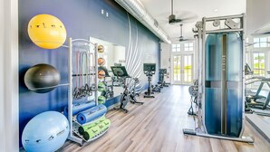 A gym with exercise equipment, a mirrored wall, and a blue wall with a fitness mural. - Golf-View Palmilla Beach retreat with pool, private garage, & alfresco dining (Port Aransas)