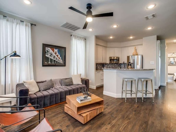 A modern living room with a sofa, coffee table, and a kitchen area with a bar.