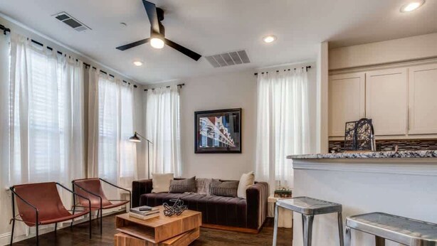 Een moderne woonkamer met een bank, twee stoelen, een salontafel en een barstoel.
