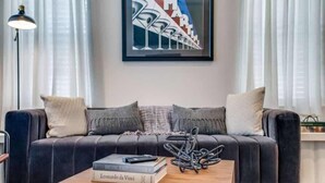 Een moderne woonkamer met een donker leren bank, een houten salontafel en een lijst met een abstract schilderij aan de muur.