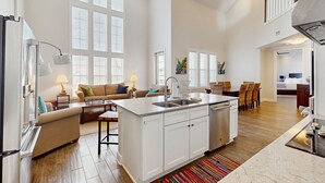 A spacious kitchen with a central island, white cabinetry, and a dining area with a sofa and chairs. - Gulf-View Palmilla Resort Condo | Pool, On-Site Dining & Beach Boardwalk (Port Aransas)
