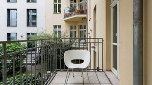 A balcony with a white chair, a metal railing, and a view of neighboring buildings. - Top Luxury Space Spree Mitte Berlin (Berlin)