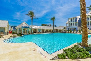 A swimming pool surrounded by palm trees and buildings with a clear blue sky.