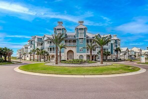 Stunning building with a classic facade, central entrance, and two towers, set amidst a beautifully manicured lawn and palm trees.