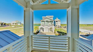 Un portico coperto con vista su una grande casa e una spiaggia.