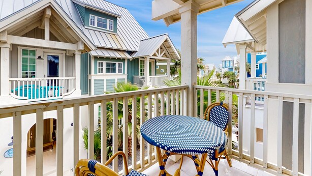 A balcony with a white railing, a blue woven table, and two wicker chairs. - Upscale townhouse near the pool with bikes, resort boardwalk & golf course (Port Aransas)