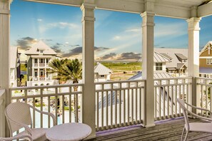 Relax in a serene outdoor space with a deck, wicker chairs, and a small table overlooking a residential area.