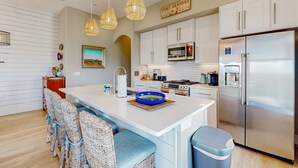 A modern kitchen with white cabinetry, a stainless steel refrigerator, and a central island with seating.