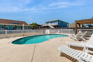 Relax by the pool surrounded by a sandy deck and lounge chairs.
