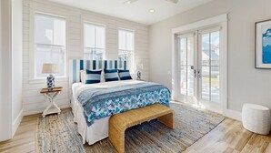 Ein Schlafzimmer mit Bett, einer Bank, einem Deckenventilator und Blick ins Freie.