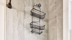 A bathroom with a white bathtub, a shower with a handheld showerhead, and a metal towel rack. - Downtown Main Street One-Bedroom Suite w/ Hi-Speed Wifi (Shelbyville)