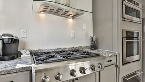 A kitchen with a gas stove, built-in oven, and a coffee maker. - Downtown Main Street One-Bedroom Suite w/ Hi-Speed Wifi (Shelbyville)