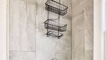 A bathroom with a white bathtub, a shower with a handheld showerhead, and a metal towel rack.
