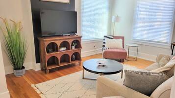 A living room with a TV, a wooden entertainment unit, a round coffee table, and a sofa.