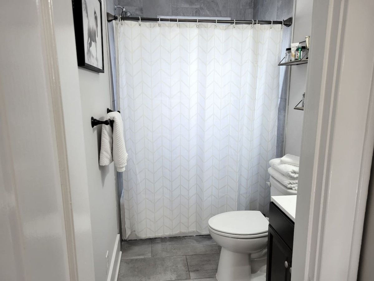 Un baño con inodoro, lavamanos, cortina de ducha y toallero.