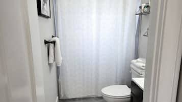 Un baño con inodoro, lavamanos, cortina de ducha y toallero.