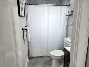 Un baño con inodoro, lavamanos, cortina de ducha y toallero.