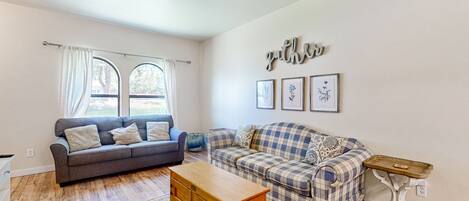Relax in a spacious living room with two sofas, a coffee table, and framed artwork.