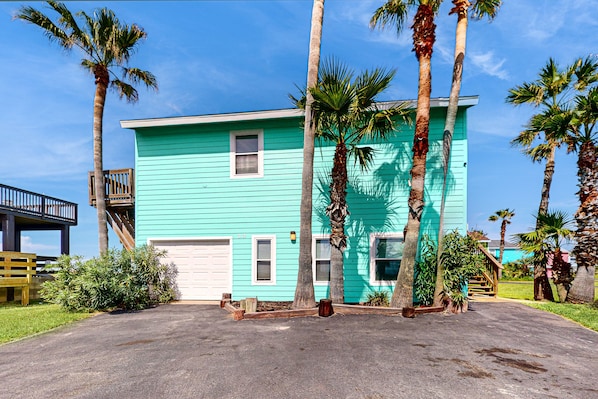 Stroll through the front yard, surrounded by palm trees, to the welcoming wooden deck.