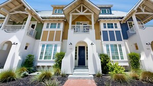 A multi-story residential building with a symmetrical facade, a central entrance with a dark door, and a small balcony on the upper floor. - Luxe Townhome in Palmilla Beach Resort | Beach Service, Pool & Golf Course (Port Aransas)