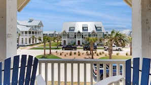 A balcony with a view of a large, multi-story building with a modern architectural style, featuring a mix of traditional and contemporary elements. - Luxe Townhome in Palmilla Beach Resort | Beach Service, Pool & Golf Course (Port Aransas)
