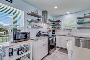 Equipped with a microwave, toaster, and coffee maker, this kitchen offers ample storage and a window with blinds.