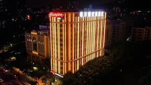Un hotel con un llamativo letrero de 'Hampton', iluminación vertical y un estilo arquitectónico clásico.