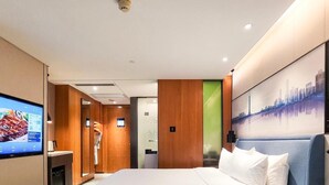 Una habitación de hotel moderna con una cama grande, un televisor, un escritorio y un cuadro de un paisaje urbano.