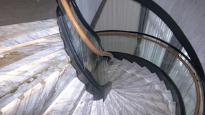 Una escalera de caracol con suelo de mármol y cerramiento de cristal.
