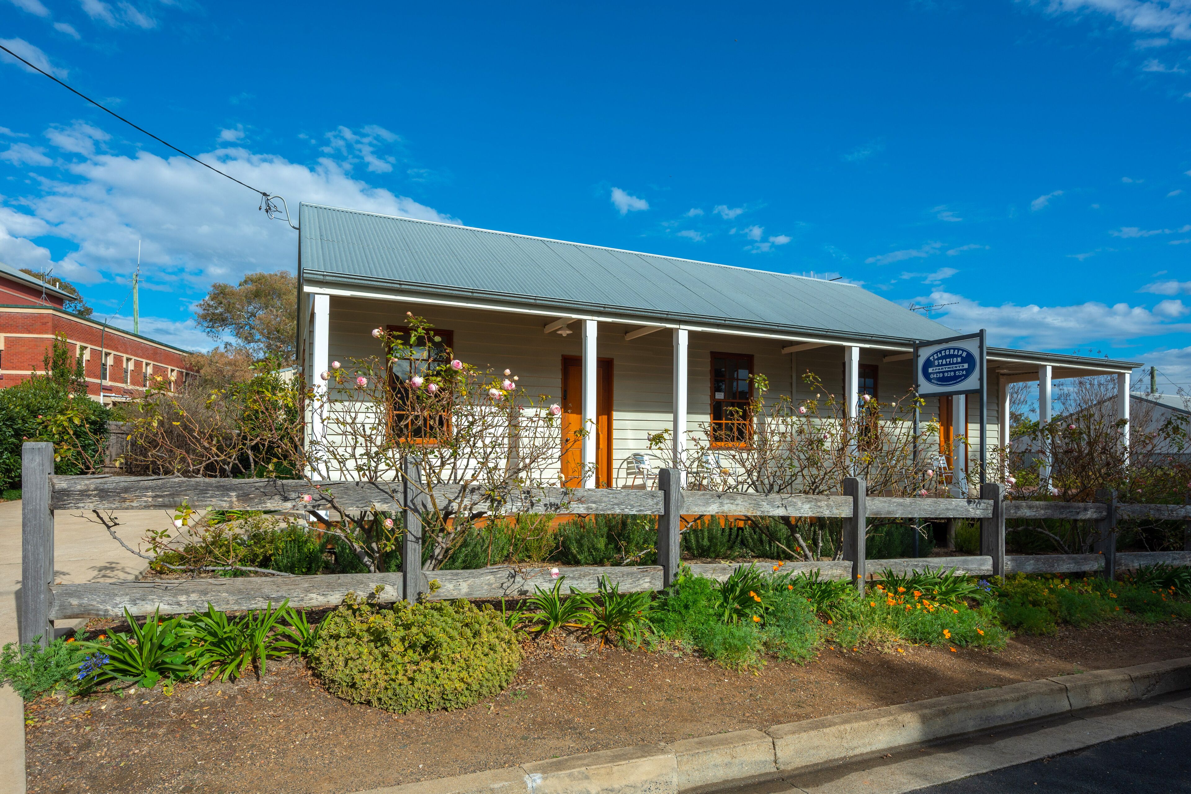 A two-story building with a porch, a signboard, and a wooden fence.