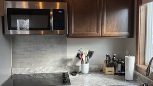 A modern kitchen with stainless steel appliances, wooden cabinets, and a marble countertop. - River Rest Luxury Cabin - The Big Hole. Beautiful River and Mountain Views!! (Silver Star)