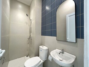 A bathroom with a toilet, sink, and shower.