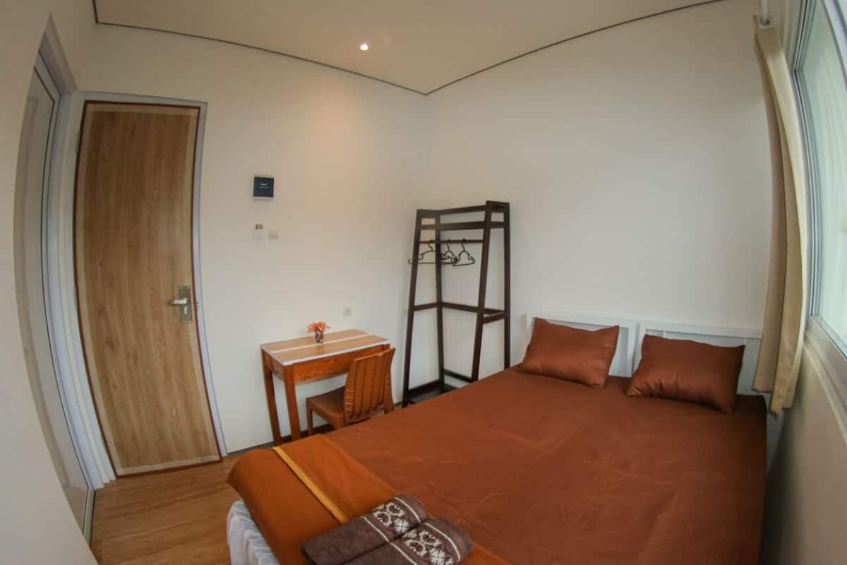 A bedroom with a bed, a desk, and a wardrobe.