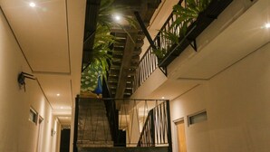 A multi-level interior with a staircase, black railings, and potted plants.