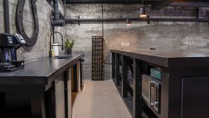 A modern kitchen with a concrete backsplash, a coffee machine, a wine rack, and a built-in oven.