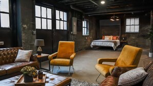 A spacious room with a large bed, two armchairs, a leather sofa, and a small table with a tray.