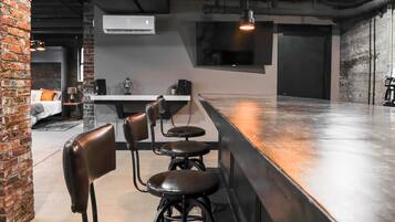 A bar area with stools, a counter, and a television mounted on the wall.