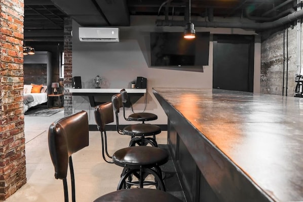 A bar area with stools, a counter, and a television mounted on the wall.