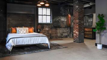 A bedroom with a bed, a hanging punching bag, a window, and a brick wall.