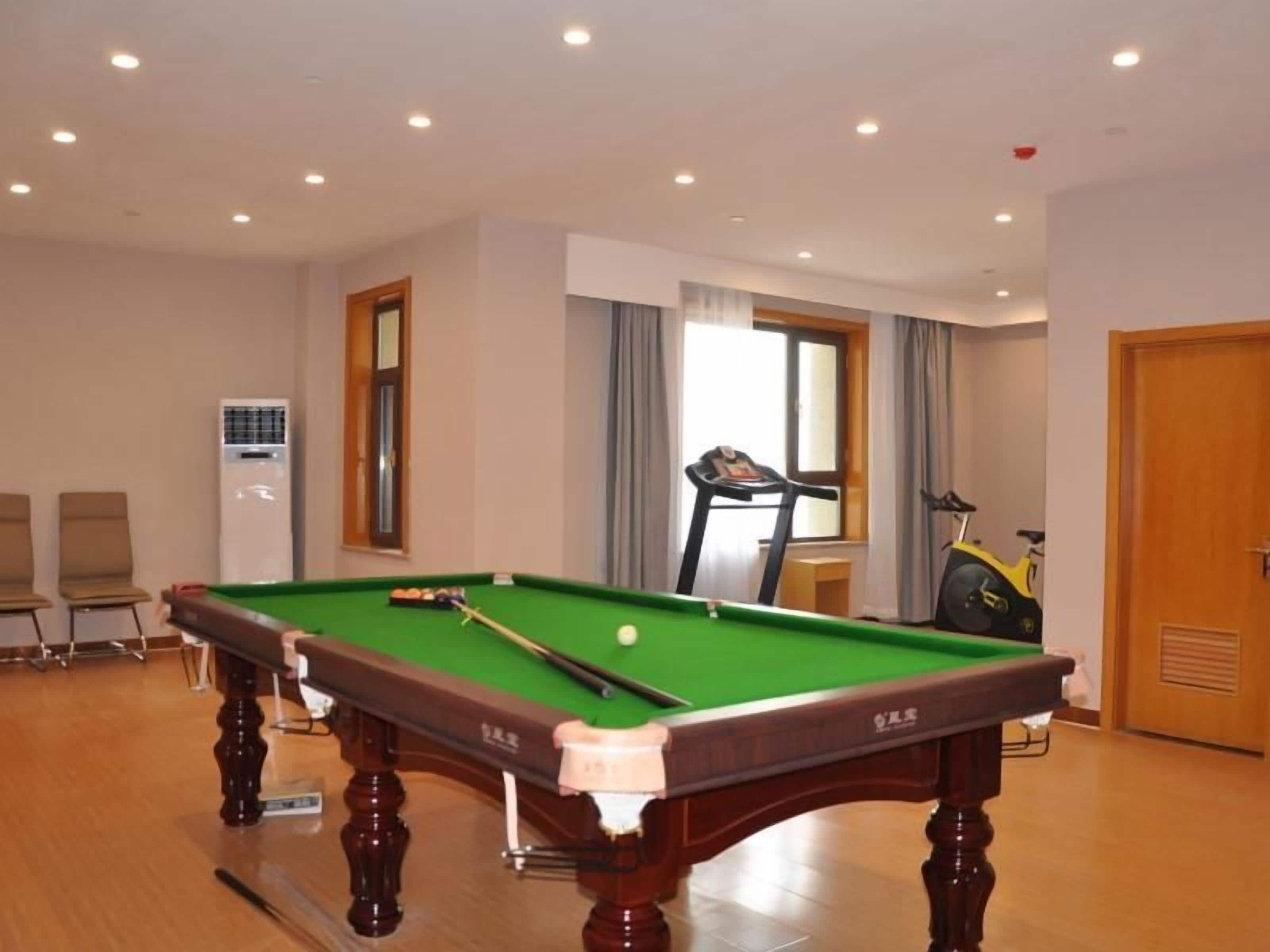 A pool table in a room with a window, a treadmill, and a door.